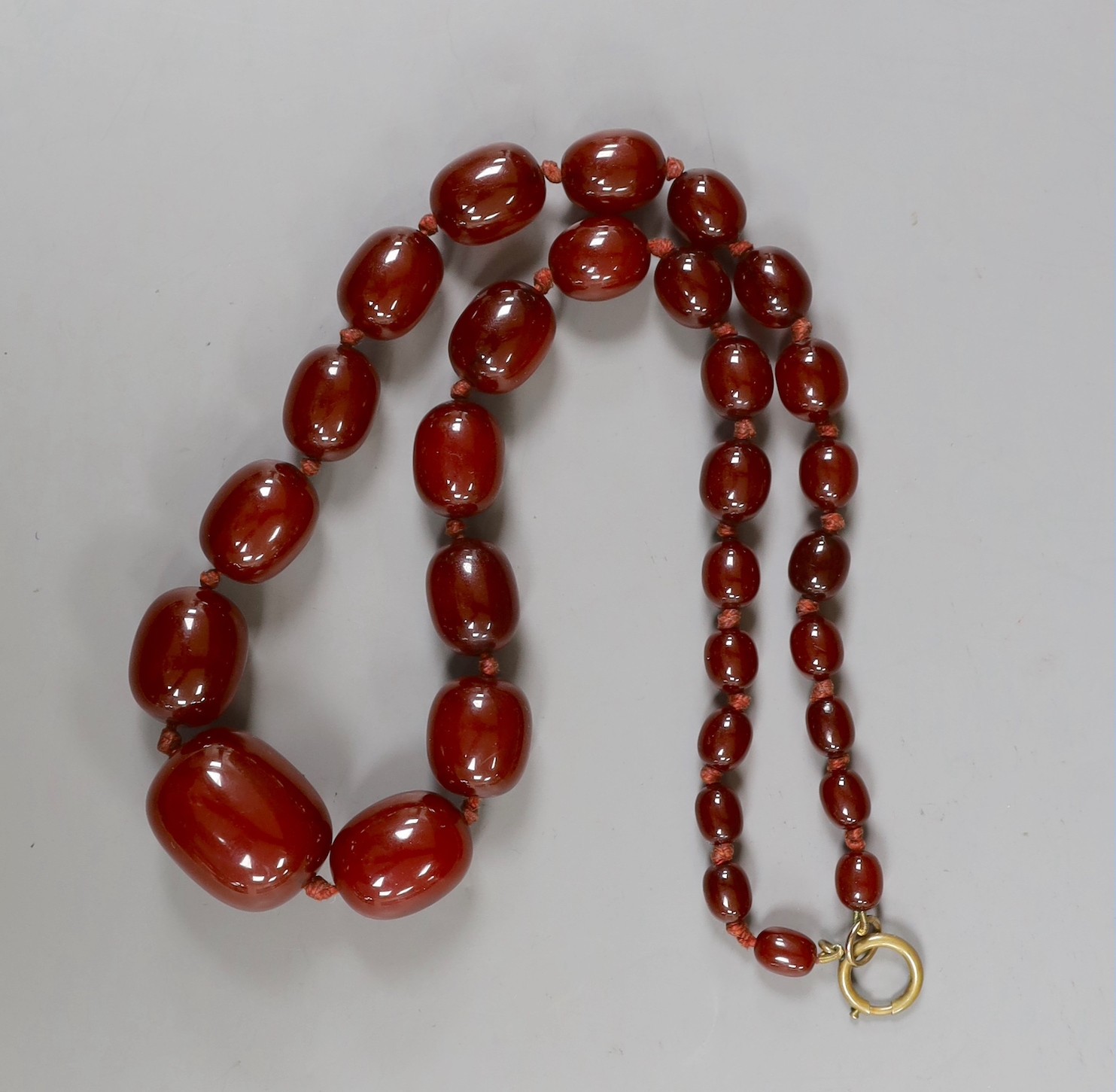 A single strand graduated oval simulated cherry amber bead necklace, 56cm, gross weight 75 grams.